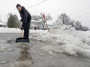 Eric Francis shovels water and slush from the driveway of his family's home in Pointe-Claire last Thursday.
