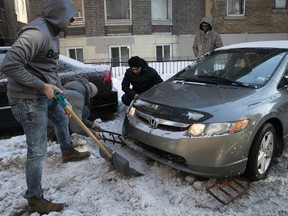 Gursimran Jeet Singn Tiwana puts snow grips under his car as his friends help him to get his car out of the ice on Lincoln av. in Montreal on Friday January 25, 2019.