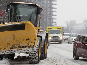 A snow-removal worker moves his vehicle onto the sidewalk and gestures to motorists to make way for an ambulance on Cote-des-Neiges Rd. on Wednesday January 23, 2019.