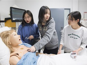 Chinese nursing exchange students, from left, Nancy Xu, Etta Zhou and Nicole Zhu tend to a mannequin at Vanier College in Montreal Jan. 28, 2019.