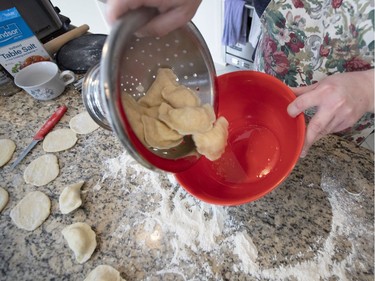 Here varenyky that have been par-boiled and drained are tossed with melted butter so they don't stick to each other. They will be laid out on a cookie sheet, cooled, frozen and placed in resealable plastic bags until Ukrainian Christmas Eve on Jan. 6, when they make up a part of the traditional 12-dish dinner served. (Allen McInnis / MONTREAL GAZETTE)