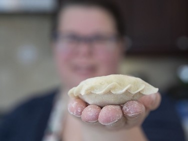 Diane Zalusky holding one of the dozens of varenyky she prepares as one of 12 dishes served at the traditional Ukrainian Christmas Eve dinner. She fills some with a mix of mashed potato and farmer's cheese and others with sauerkraut bound with a bit of mashed potato. She finishes the edge of the two kinds in slightly different ways so that one is distinguishable from the other in the freezer and on the table. Here she demonstrated a braided edge she uses for the varenyky filled with sauerkraut and a bit of potato: The potato-cheese variety has more of a plain edge. (Allen McInnis / MONTREAL GAZETTE)