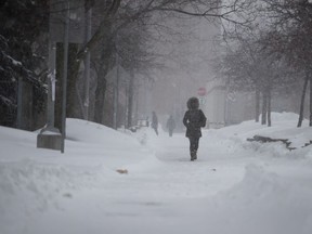 A pedestrian walks along a snow path as she heads to Lionel-Groulx métro station during the first snowstorm of the season in Montreal on Sunday, Jan. 20, 2019.