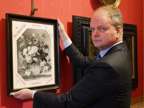 A handout picture realeased by the Florence Museum Press Office on January 1, 2019 shows the Florence Uffizi Galleries director Eike Schmidt posing past a copy of the "Vase of Flowers" by Dutch painter Jan van Huysum, stolen from the Wehrmacht's Pitti Palace during World War II, in Florence. - The Uffizi Gallery in Florence on January 1, 2019 appealed to Berlin for help in retrieving a stolen 18th century Dutch painting from a German family. According to Schmidt, the oil painting is "currently held by a German family who, after all this time, has still not returned it to the museum despite many requests by the Italian state."