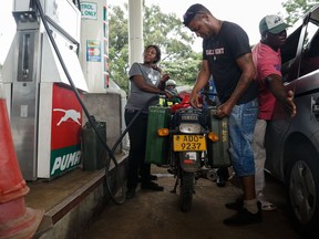 A petrol attendant serves a motorcyclist with two jerry cans attached to his motorbike at a fuel station, on January 11, 2019 in Harare. Motorists are spending nights waiting in long queues for petrol and diesel as the country is experiencing  crippling fuel shortages.