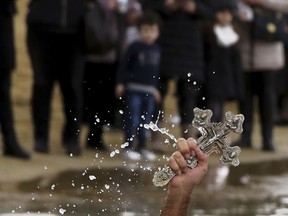 A swimmer holds up the cross after it was thrown from an Orthodox priest into the water, during an epiphany ceremony to bless the sea at Famagousta or Varosia beach in the Turkish Cypriots breakaway north part of the eastern Mediterranean divided island of Cyprus, Sunday, Jan 6, 2019. Many Orthodox Christian faithful attended the Epiphany Day blessing of the waters in Famagusta in Cyprus', the fourth time the ceremony has taken place since 1974 when the small island nation was cleaved along ethnic lines.