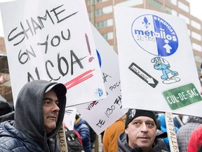 Members of Steelworker Unions hold up signs during a protest in Montreal, Wednesday, November 28, 2018, where they demonstrated against a lockout of workers at an Alcoa smelter plant in Becancour, Que. With a negotiation deadline looming, the United Steelworkers union has filed a complaint with Quebec's labour board alleging bad faith bargaining by Alcoa Corp. at its aluminum smelter near Trois-Rivieres, where unionized workers have been locked out since January.