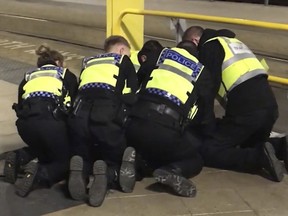 Manchester police restrain a man after three people — including a British Transport Police officer — were stabbed at Victoria Station in Manchester, England, late Monday Dec. 31, 2018.