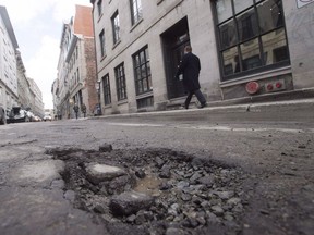 A pothole is seen on St-Paul St. on March 18, 2016 in Montreal. Municipal and provincial governments in Canada are all looking for better ways to deal with their growing pothole problems, but none are properly tracking whether the repairs they do now are effective over time, says the author of a soon-to-be completed study on the roadway menaces.