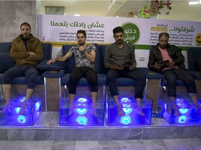 Palestinians soak their feet in tank stocked with doctor fish at a cafe in Gaza City.