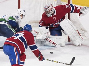 Canucks' Antoine Roussel moves in on Canadiens goaltender Carey Price, while defenceman Brett Kulak trails on the play during the third period Thursday night at the Bell Centre.