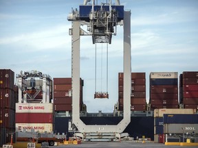 FILE- In this July, 5, 2018, file photo photo, a ship to shore crane prepares to load a 40-foot shipping container onto a container ship at the Port of Savannah in Savannah, Ga. The higher costs resulting from the tariffs have yet to inflict much overall damage to a still-robust American economy, which is less reliant on international trade than most other countries are. Spurred by lower taxes, the economy grew at an impressive 3.4 percent annual rate from July through September after having surged 4.2 percent in the previous quarter. And employers added 2.6 million jobs last year, the most since 2015.