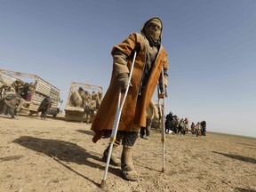 A man uses crutches to walk as people who fled battles between Syrian Democratic Forces (SDF) and fighters from ISIL in the Syrian village of Baghuz, arrive after crossing a desert in the back of a truck to a region controlled by the SFD on January 26, 2019.