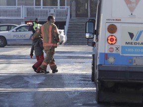 A firefighter walks a young child to waiting STM bus after an elementary school in LaSalle, École des Decouvreurs, was evacuated on Jan. 14, 2019.