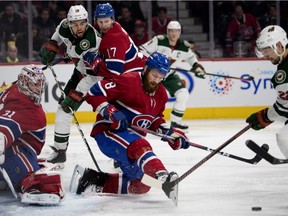 Montreal Canadiens defenceman Jordie Benn kicks the puck past Minnesota Wild right-wing Nino Niederreiter as Brett Kulak ties up Wild's eft wing Jordan Greenway, rear, in Montreal on Jan. 7, 2019.