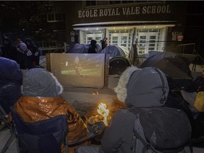 On Feb. 3, 2019, parents keep warm with a fire, and watch the Super Bowl in front of École Royal Vale in Montreal in anticipation of getting a place for their children starting kindergarten.