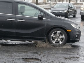 A mini-van hits a deep pothole at the intersection of Source and Hymus boulevards on Feb. 8.