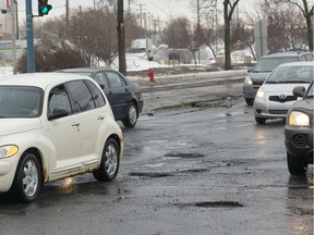 Cars weave to avoid deep potholes at the intersection of Sources Blvd. and Hymus Blvd. last month.