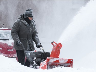 A man is enveloped in blowing snow as he cleans a driveway on Noorduyn Street in Ville St. Laurent, Montreal, Monday February 13, 2017, following a snowstorm that dumped up to 23cm of snow in some places.