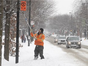 A Montreal city worker puts up no parking signs ahead of snow-clearing operations on Iberville St.