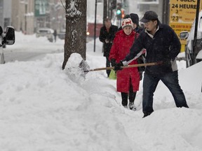 Danny Lee shovels the sidewalk outside his business after the city failed to clean the sidewalks on Metcalfe Street in Montreal, on Wednesday.