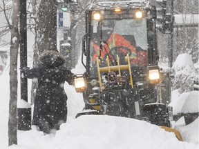 Montreal resident walks past sidewalk cleaner on Christophe-Colomb and Jean-Talon, following snowstorm Feb. 13, 2019.
