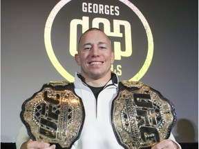 Georges St-Pierre holds up his championships belts after announcing his retirement from UFC mixed martial arts competition at a news conference in Montreal on Thursday, Feb. 22, 2019.