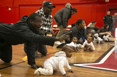 Olufemi Imam encourages his 9-month-old daughter Asimah to crawl towards the finish line during a baby race in Montreal on Feb. 23, 2019.