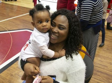 Josephine Akinrinola holds her 7-month-old baby Alexandra after she crosses first over the finish line during a baby race in Montreal on Feb. 23, 2019.