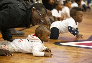 Olufemi Imam encourages his 9-month-old daughter Asimah to crawl towards the finish line during a baby race in Montreal on Feb. 23, 2019.