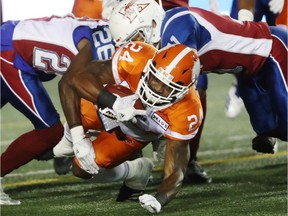 BC Lions' Jeremiah Johnson is taken down by Montreal Alouettes' Tevaughn Campbell (26) and Chip Cox (11) in Montreal on Sept. 14, 2018.