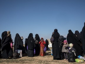 Civilians who have fled fighting in Bagouz wait to board trucks after being screened by members of the Syrian Democratic Forces (SDF) at a makeshift screening point in the desert on Saturday, Feb. 9, 2019 in Bagouz, Syria.
