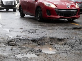 Motorists wait for a chance to use the oncoming traffic lane to avoid a pothole measuring 7 inches deep and almost 4 feat across on Notre-Dame Street in the Southwest district of Montreal, on Thursday, February 7, 2019.