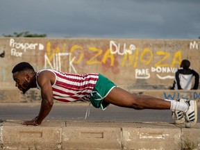 Emmanuel Sibanda, a 25-year-old mechanical engineer, does push ups early in the morning Jan. 27, 2019, in Zimbabwe. This wide stretch of road is a well-known gathering spot each morning for fitness enthusiasts.