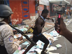 Haitian police try to arrest a man who was caught looting a shop in Port-au-Prince Feb. 12, 2019, as a sixth day of protests against Haitian President Jovenel Moise and the misuse of Petrocaribe funds continued.