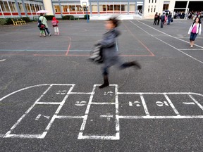 A child plays hopscotch in a schoolyard.