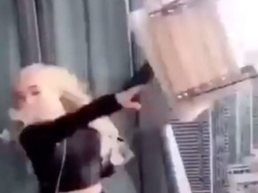 A woman throws a deck chair from a highrise condo balcony towards the Gardiner Expressway in Toronto in video posted to social media.