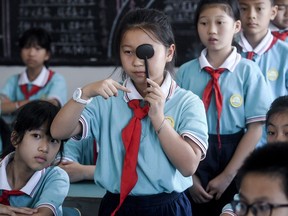 In this Sept. 4, 2018, photo released by Xinhua News Agency, students line-up to get eyesight test at a primary school in Donglin Township of Huzhou City, east China's Zhejiang Province. An eastern Chinese province plans to ban teachers from assigning homework to be completed on cellphone apps as part of efforts to preserve students' eyesight. Zhejiang province issued a draft regulation last week and is seeking public comment. (Xu Yu/Xinhua via AP) ORG XMIT: XIN801