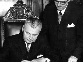 Prime Minister John Diefenbaker signs Montreal's Golden Book as Mayor Jean Drapeau looks on, during a visit to the city Feb. 16, 1961.