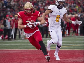 Laval Rouge et Or's Felix Faubert-Lussier scores his first touchdown against Laurier Golden Hawks' Isaiah Guzylak-Messam runs behind during first quarter action at the Uteck Bowl on Nov. 19, 2016, in Quebec City.