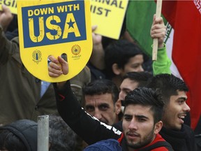 A demonstrator holds an anti-U.S. placard during a ceremony celebrating the 40th anniversary of the Islamic Revolution, at the Azadi, Freedom, Square in Tehran, Iran, Monday, Feb. 11, 2019. Crowds streamed in the rain from a dozen of the capital's far-flung neighborhoods to mass in central Tehran, waving Iranian flags and chanting "Death to America" -- a chant that has been standard fare at anti-U.S. rallies across Iran.