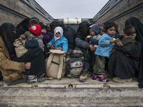 Woman and children who fled ISIL's embattled holdout of Baghouz on February 14, 2019, wait in the back of a truck in the eastern Syrian province of Deir Ezzor.