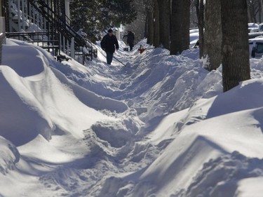 A man cleans the sidewalk on D'Aragon street in the Côte-St-Paul area of Montreal Wednesday, January 2, 2008, after the first major snowstorm of the New Year.