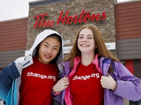 Mya Chau, left, 12, and Eve Helman, 12, who are digitally petitioning Tim Horton‚Äôs to make the roll up the rim to win campaign more environmentally friendly, are seen outside a Tim Horton's in Calgary, Alta., Sunday, Feb. 3, 2019.THE CANADIAN PRESS/Jeff McIntosh