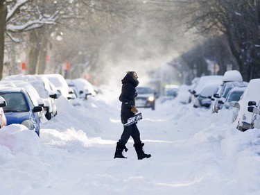 A woman carries a shovel across a snow covered street following a major snowstorm in Montreal, Sunday, January 14, 2018.