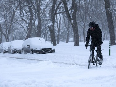 A man steers his bike on a snow-covered street during a winter storm in Montreal Feb. 13, 2019.