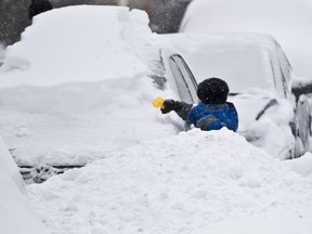 Peter Panagopoulos, 5, uses a toy shovel to clean snow off his parents' car on Thompson Street on Dec. 15, 2013, in the borough of Ville St Laurent, Montreal Sunday December 15, 2013, during a snowstorm.