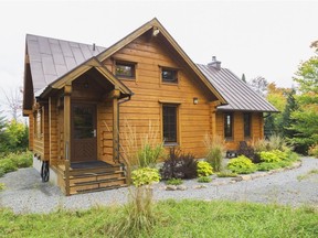 The moderate size pièce-sur-pièce structure is a rustic and elegant looking log home with Scandinavian touches, seen on the window frames outside.