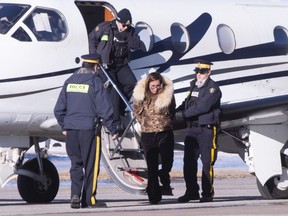 RCMP officers escort a female suspect in a money laundering network off an airplane in St-Hubert, Que. on Monday, February 11, 2019. The RCMP and other police forces arrested 15 people Monday in a series of raids in Montreal and Toronto targeting what investigators say is an extensive international money laundering network with ties to organized crime.