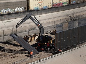 In this Tuesday, Jan. 22, 2019, photo, workers place sections of metal wall as a new barrier is built along the Texas-Mexico border near downtown El Paso.